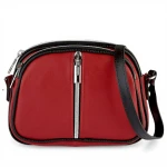 Czerwona skórzana torebka listonoszka widziana od przodu, z wyraźnym pionowym suwakiem i czarnymi lamówkami