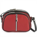 Mała czerwona torebka skórzana ukazana pod kątem, eksponująca górne zapięcia trzech niezależnych komór